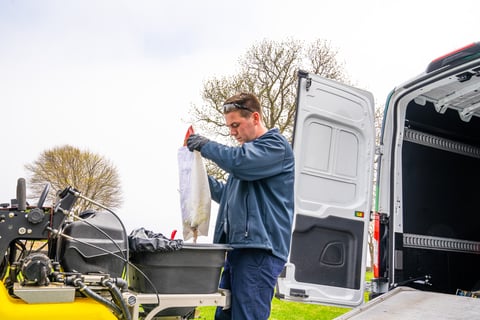 lawn care technician preparing to apply a slow-release granular fertilizer
