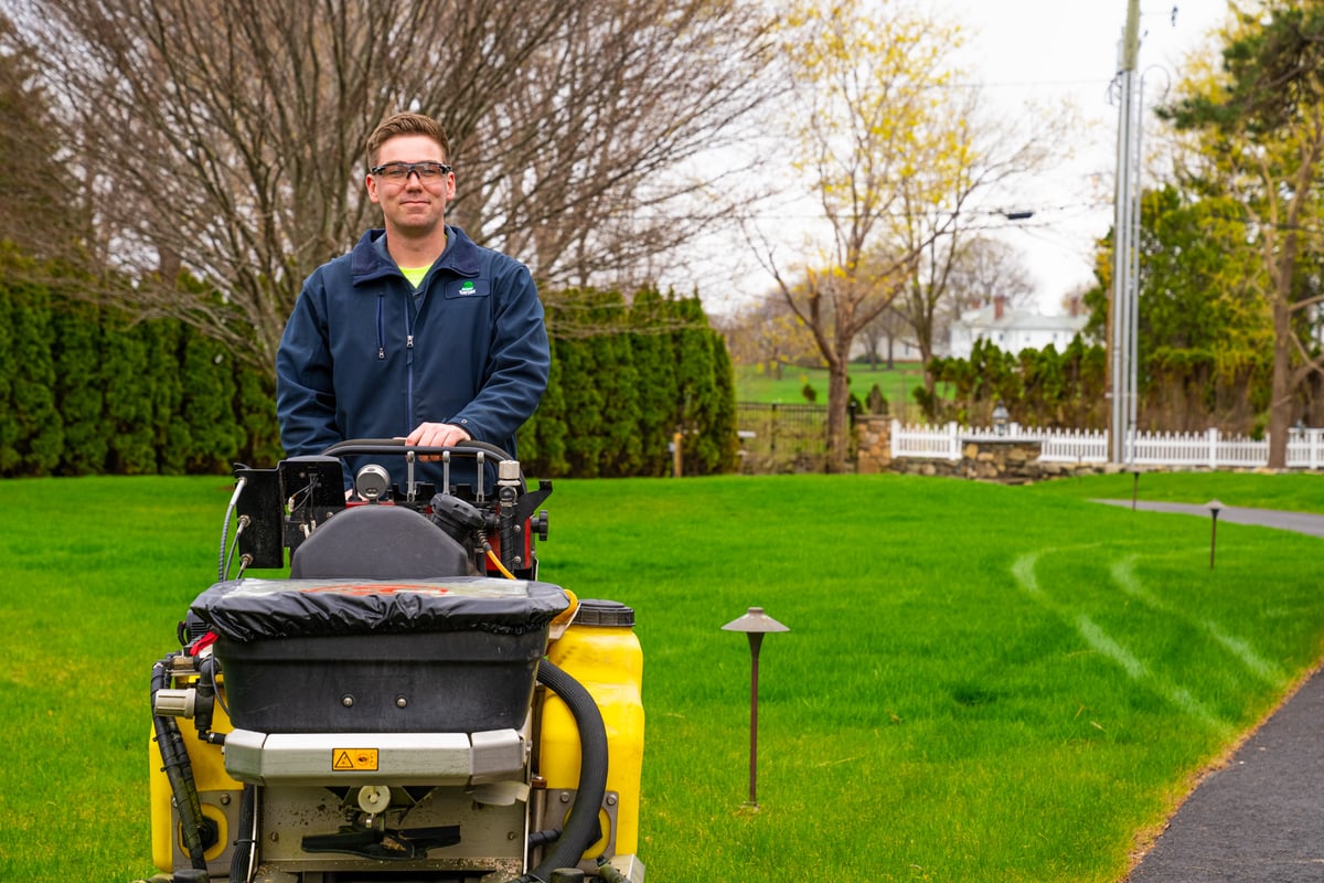 lawn care technician fertilizes grass