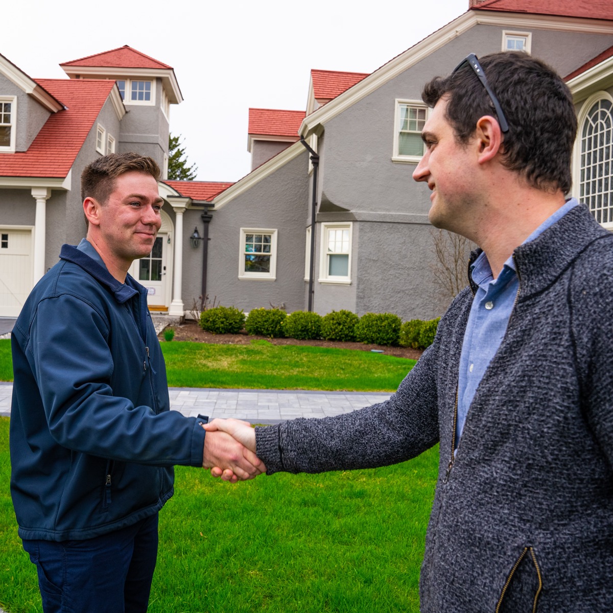 lawn care technician shakes customer's hand