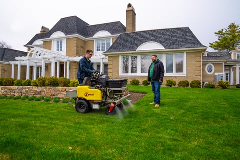 Lawn technician applying organic based fertilizer to green grass