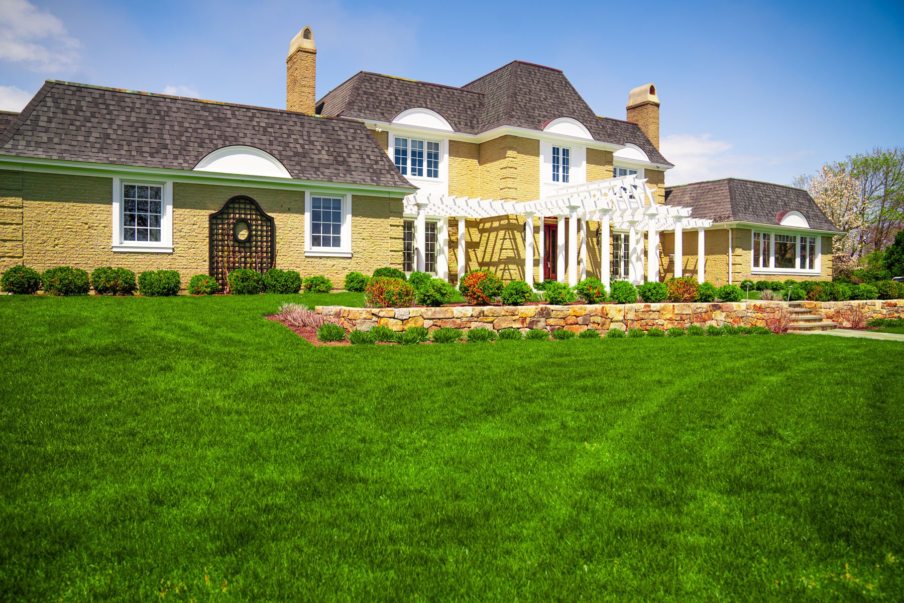 a thick, green lawn in front of a New England home