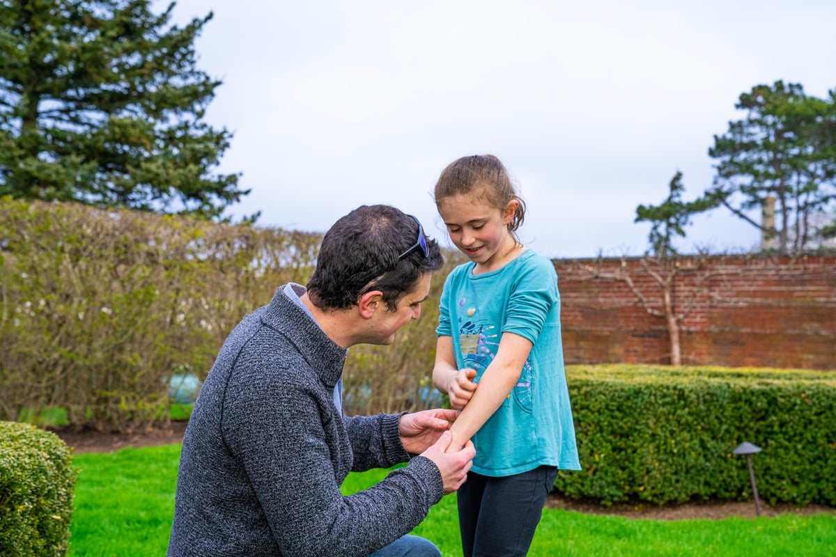 dad checks mosquito bite on child arm