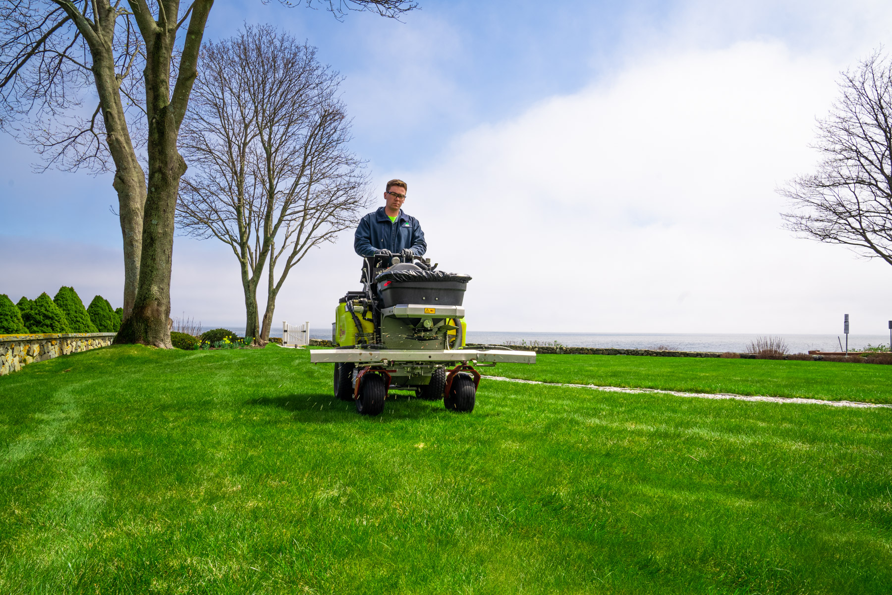 Lawn care technician fertilizing lawn in New England