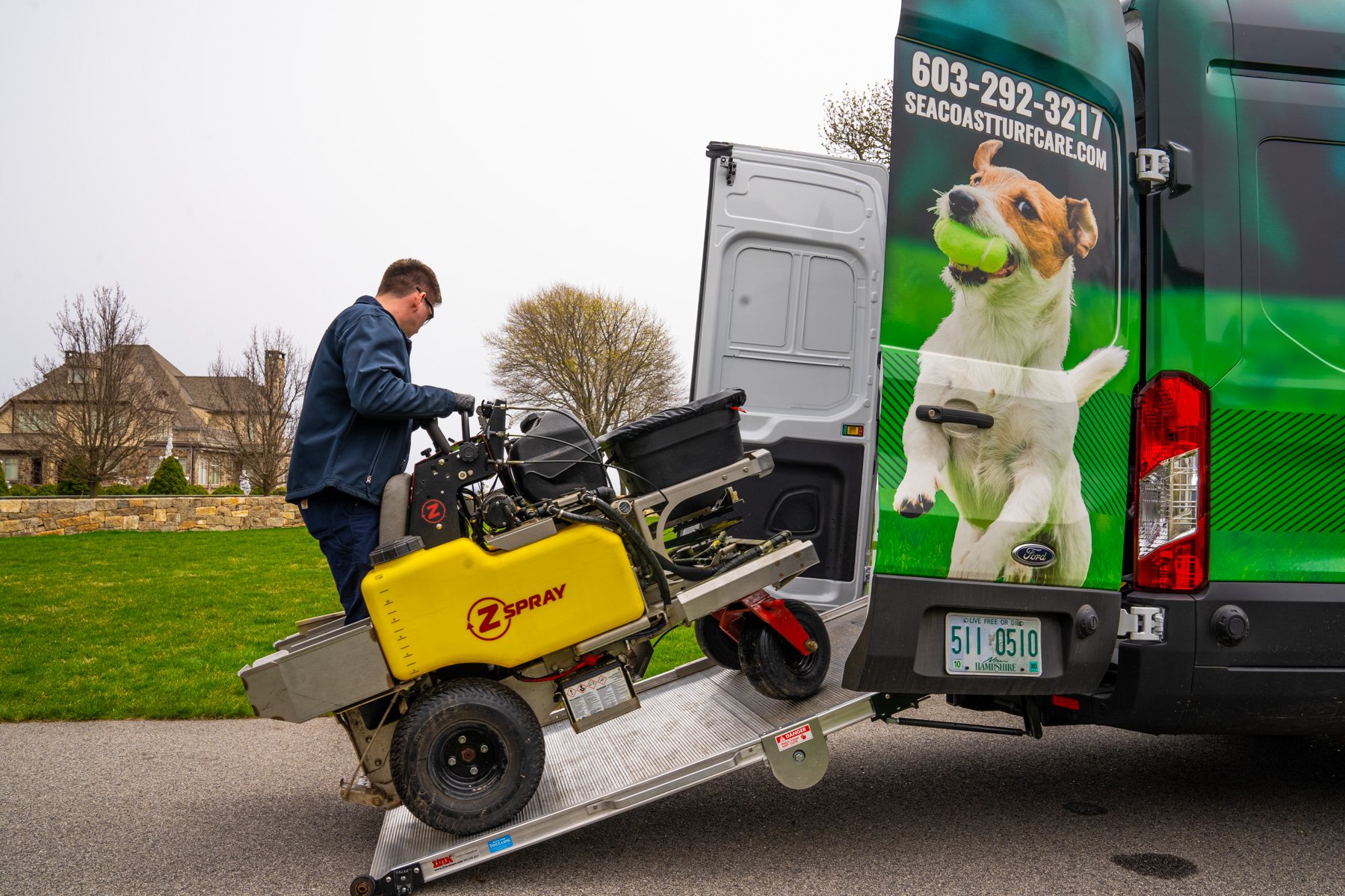 lawn care technician backs spreader out of van